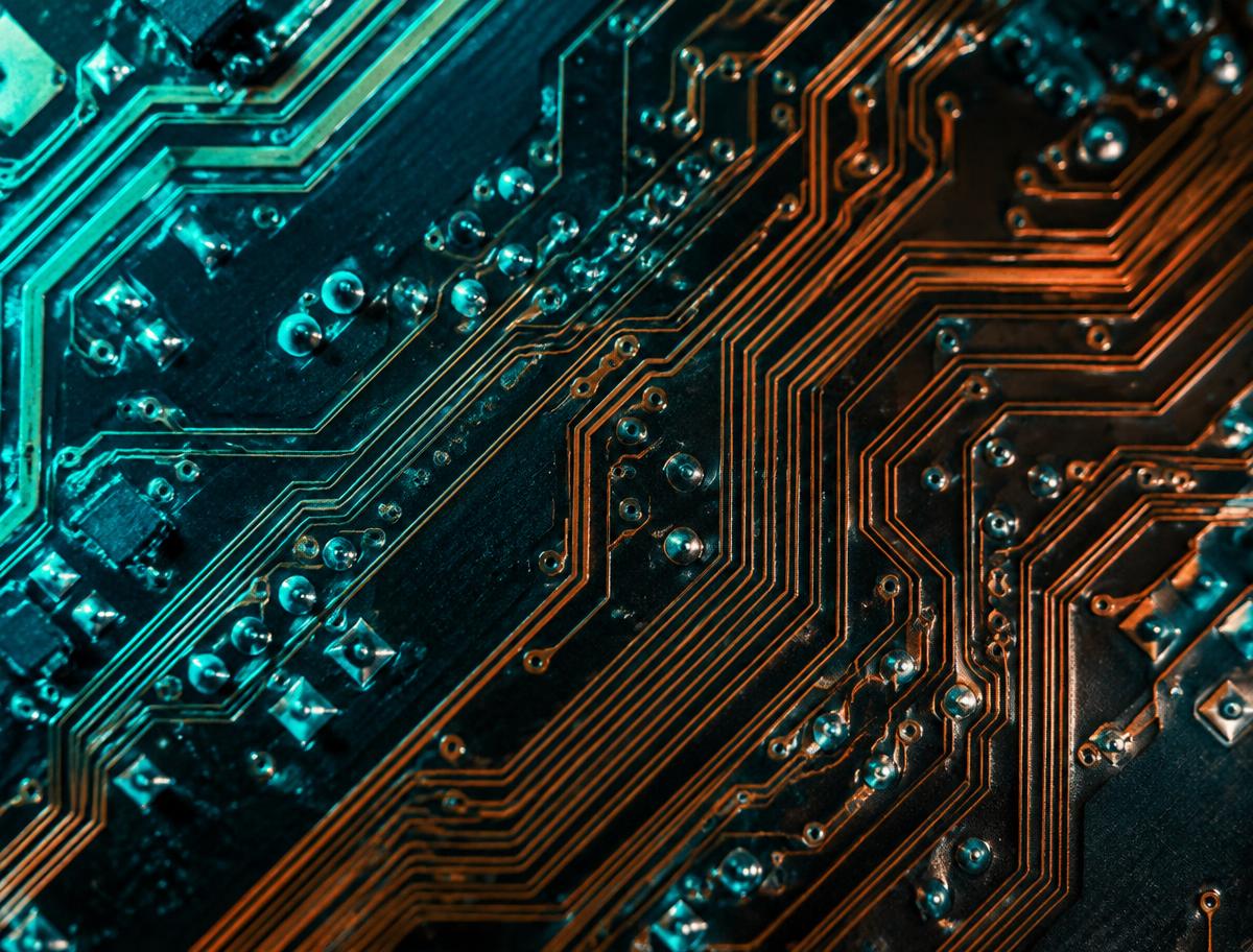 Macro view of circuit board traces lit in cyan and copper